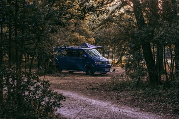 A campervan parked for a camping trip in a national park with space-saving hacks inside to better their space for the trip 