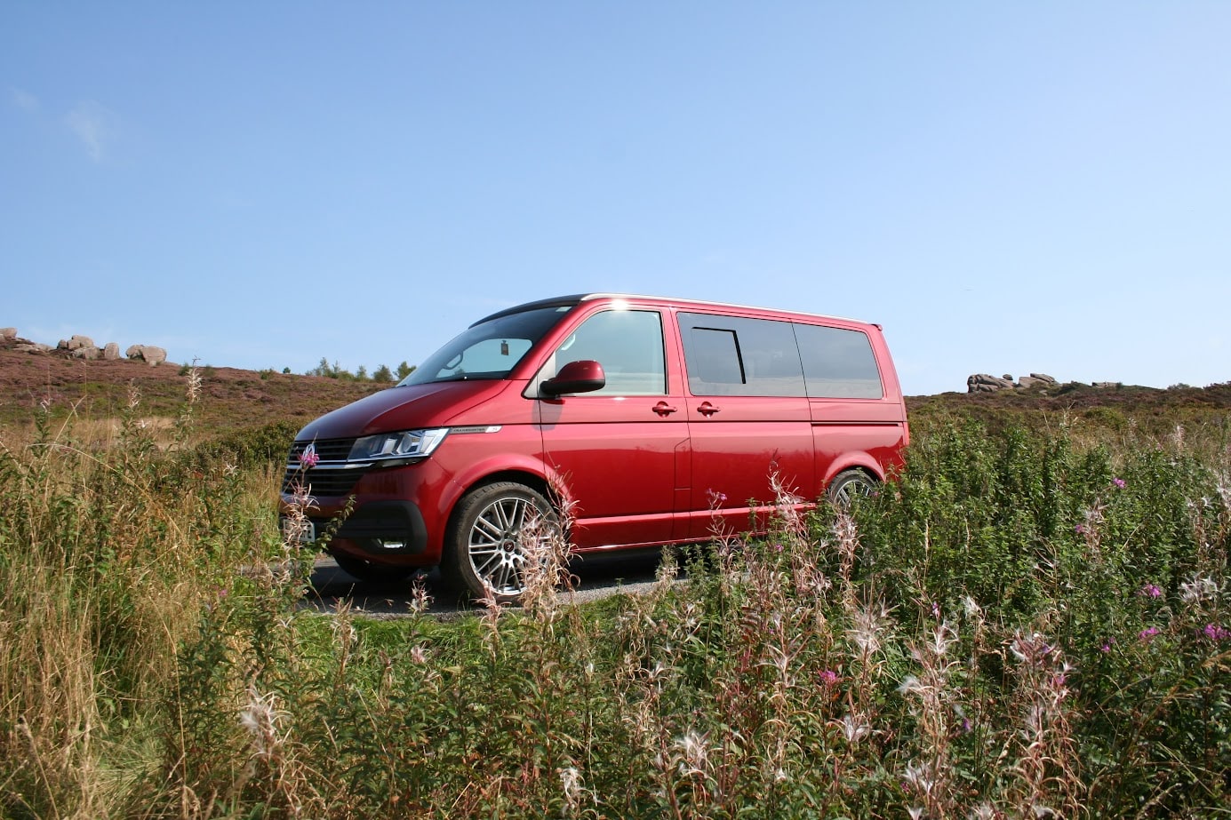 A campervan parked in a countryside field during the summer after a deep exterior clean ready to go on summer trips. 