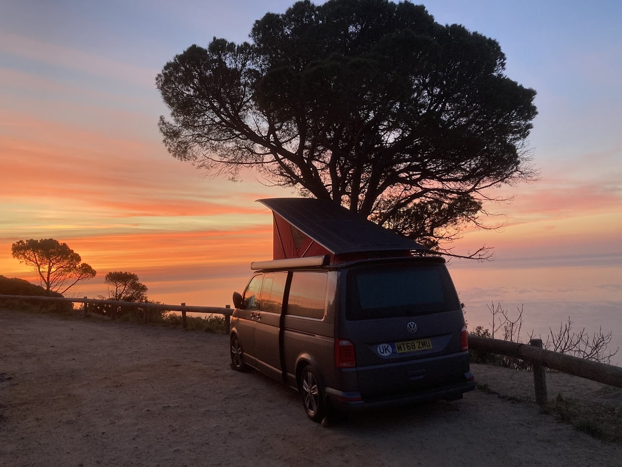 A campervan with a pop top roof parked overlooking a sunset after being taken to the best locations on the south coast of the UK. 